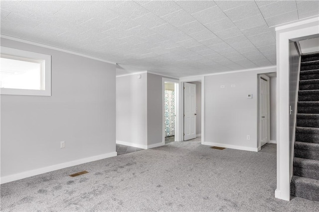 spare room with visible vents, baseboards, light colored carpet, stairs, and crown molding