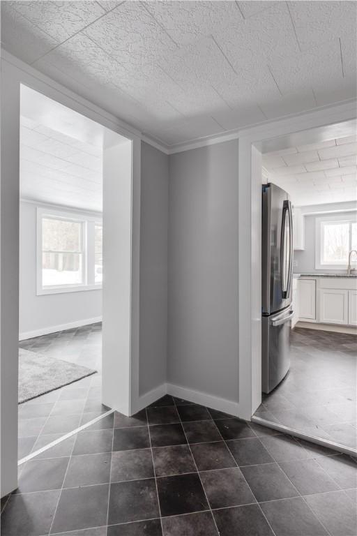 unfurnished room with a textured ceiling, dark tile patterned flooring, crown molding, and baseboards