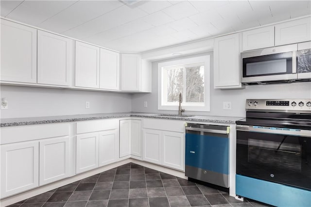 kitchen featuring light stone counters, appliances with stainless steel finishes, a sink, and white cabinetry