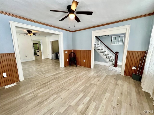 interior space with light wood-style floors, stairs, and wainscoting