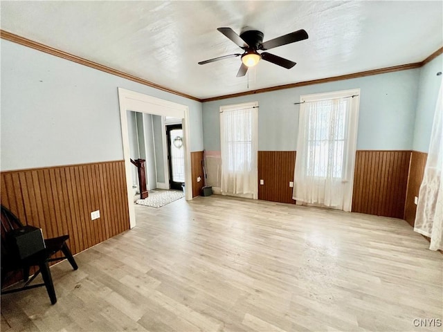 unfurnished room with light wood-style flooring, wainscoting, and wooden walls