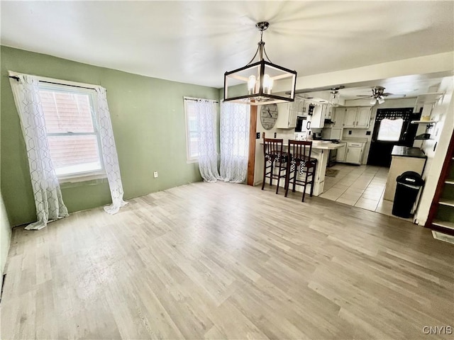 dining room with ceiling fan with notable chandelier and light wood-style floors