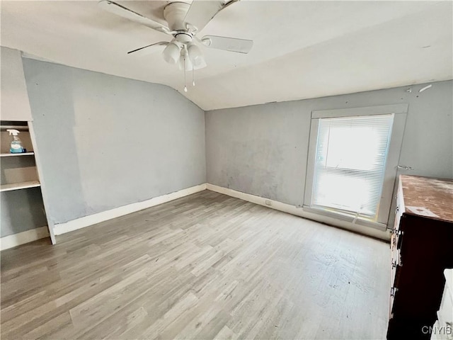 empty room featuring baseboards, vaulted ceiling, light wood finished floors, and ceiling fan