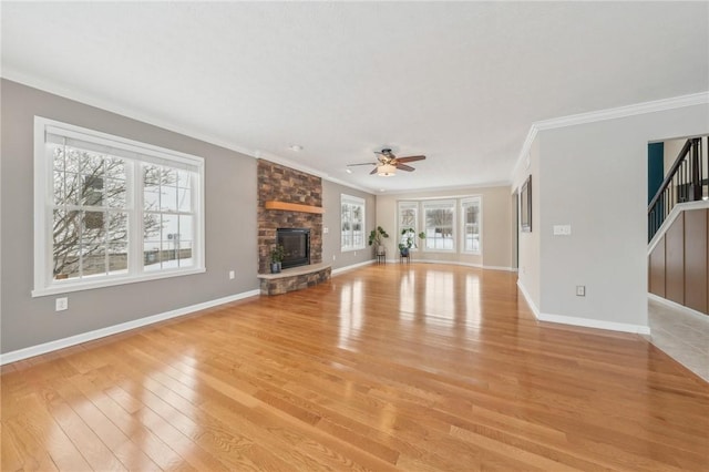 unfurnished living room featuring a fireplace, baseboards, light wood-style floors, ornamental molding, and stairway