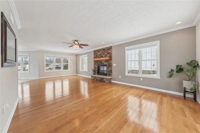 unfurnished living room with baseboards, a ceiling fan, ornamental molding, a stone fireplace, and light wood-style floors