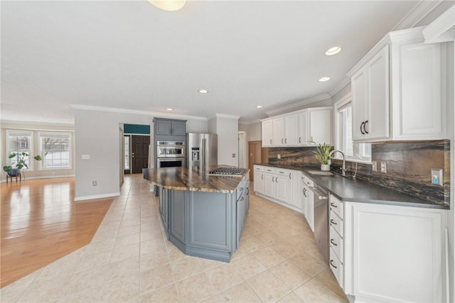 kitchen with tasteful backsplash, white cabinets, appliances with stainless steel finishes, a center island, and a sink