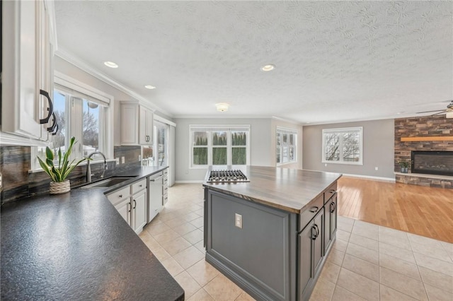 kitchen with light tile patterned floors, a sink, white cabinets, a center island, and dark countertops