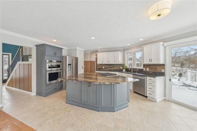 kitchen with stainless steel appliances, butcher block countertops, white cabinets, gray cabinets, and a center island