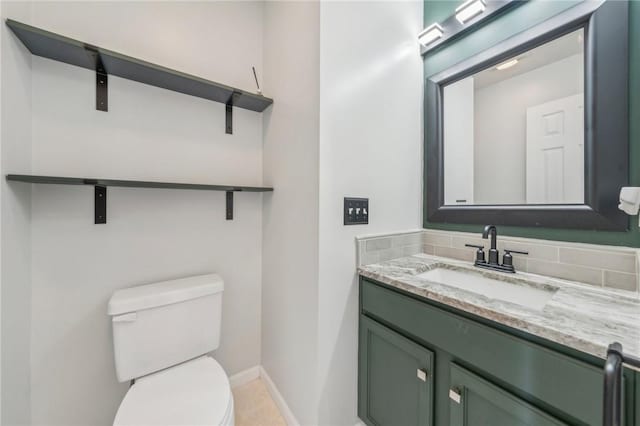 bathroom with toilet, baseboards, vanity, and decorative backsplash