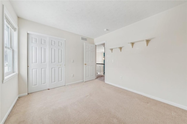 unfurnished bedroom with baseboards, a textured ceiling, and light colored carpet