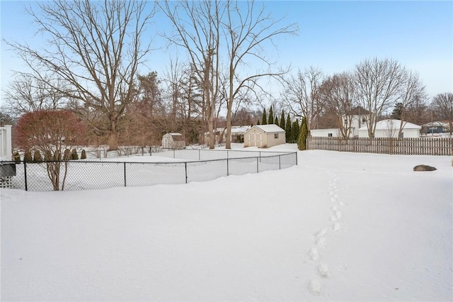 yard covered in snow featuring fence, an outdoor structure, and a shed