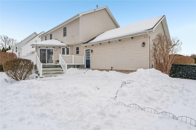 snow covered house featuring a wooden deck