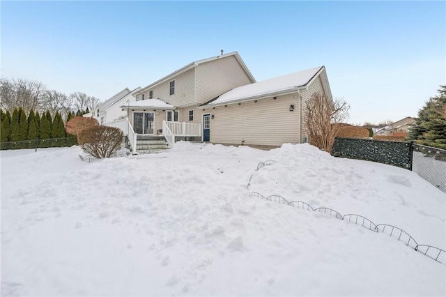 snow covered back of property with fence