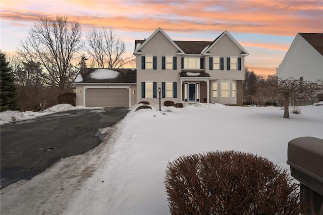 traditional-style house with an attached garage, a chimney, and aphalt driveway