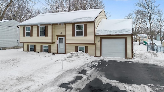 split foyer home featuring a garage and fence