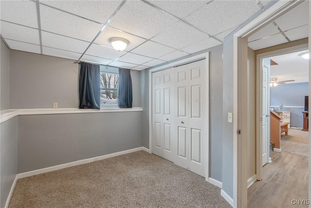 unfurnished bedroom featuring a closet, a drop ceiling, and baseboards