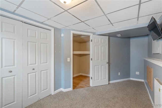 basement with carpet floors, baseboards, and a paneled ceiling