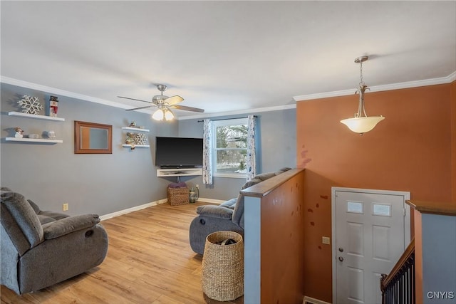 living area featuring ceiling fan, ornamental molding, wood finished floors, and baseboards