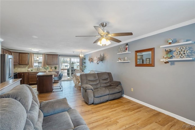 living room with light wood finished floors, ornamental molding, a ceiling fan, and baseboards