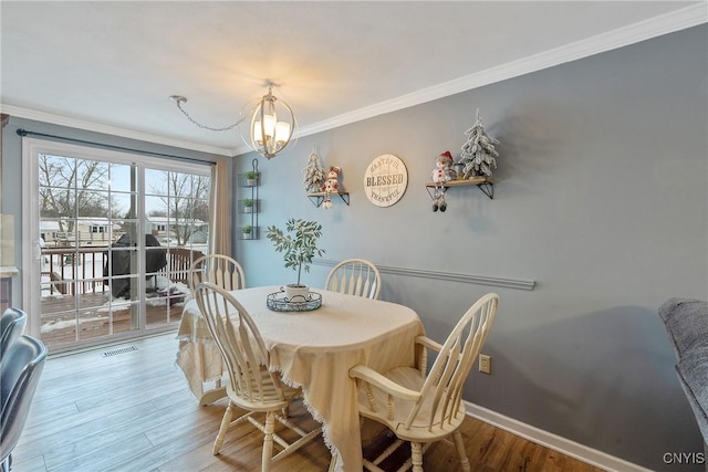 dining space featuring a notable chandelier, visible vents, baseboards, ornamental molding, and light wood finished floors