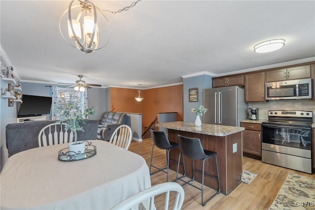 dining space featuring ceiling fan with notable chandelier, light wood-type flooring, and crown molding