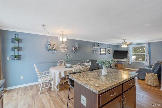 kitchen featuring open floor plan, crown molding, and light wood finished floors