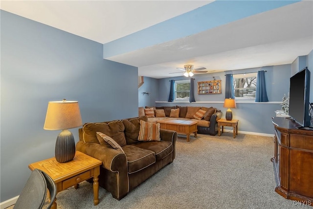 living area featuring light colored carpet, ceiling fan, and baseboards