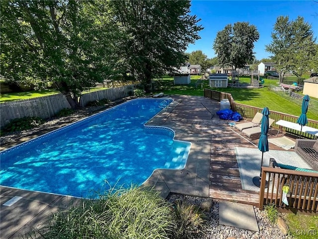 view of swimming pool with a fenced in pool, a fenced backyard, a yard, and a wooden deck