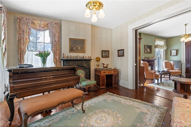 living area featuring a notable chandelier, dark wood-type flooring, plenty of natural light, and wallpapered walls