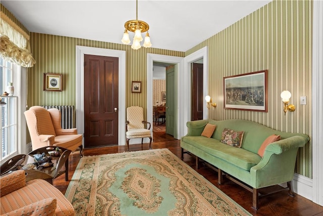 living area with wallpapered walls, wood finished floors, and an inviting chandelier