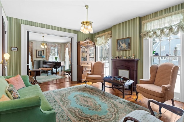 sitting room featuring wallpapered walls, a notable chandelier, and wood finished floors