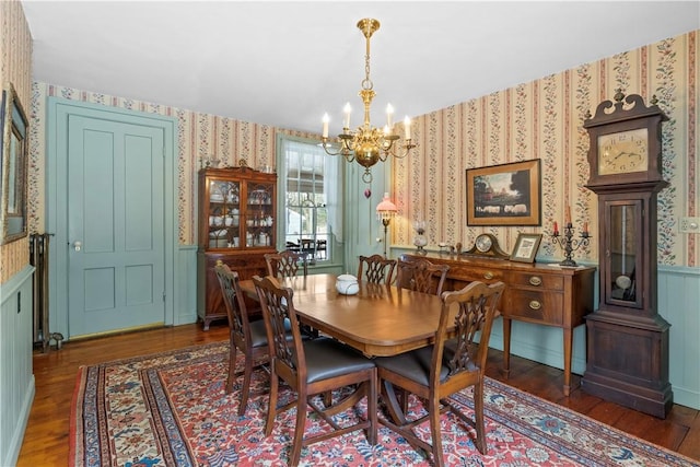 dining room featuring wainscoting, dark wood finished floors, an inviting chandelier, and wallpapered walls