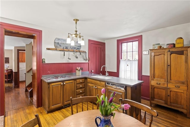 kitchen featuring a wainscoted wall, a sink, hanging light fixtures, dishwasher, and stainless steel gas stovetop