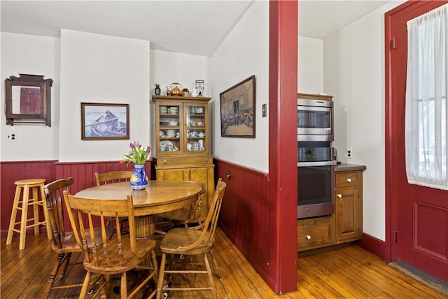 dining room with a wainscoted wall, light wood-style flooring, and wooden walls