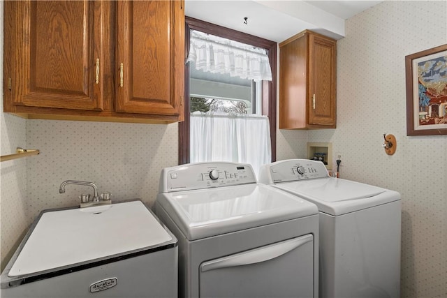 washroom featuring wallpapered walls, cabinet space, separate washer and dryer, and a sink