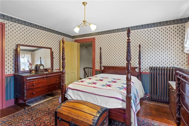 bedroom with wainscoting, dark wood-style floors, wallpapered walls, radiator heating unit, and an inviting chandelier