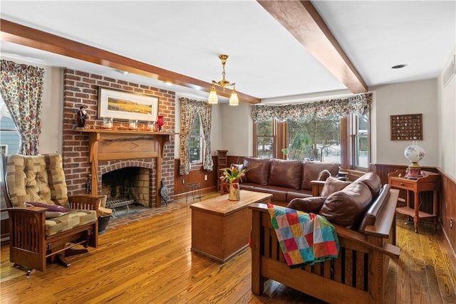 living area featuring a fireplace, wainscoting, wood-type flooring, and beam ceiling