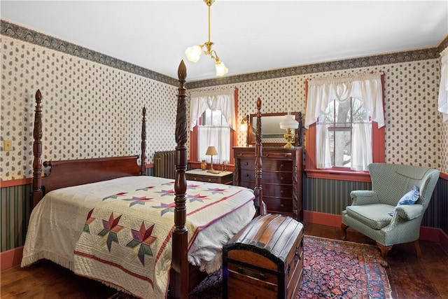 bedroom with dark wood finished floors and wallpapered walls