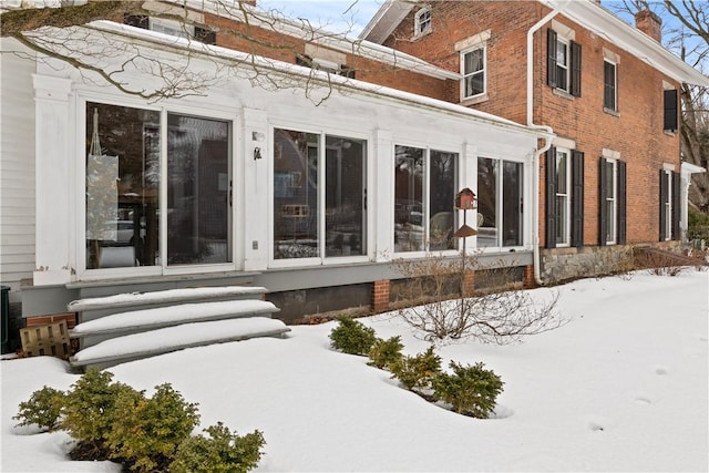 exterior space with entry steps, brick siding, and a chimney