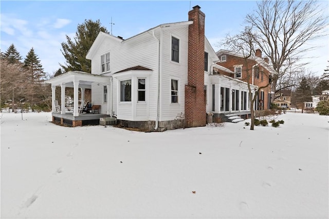 exterior space with a porch, a chimney, and central AC unit