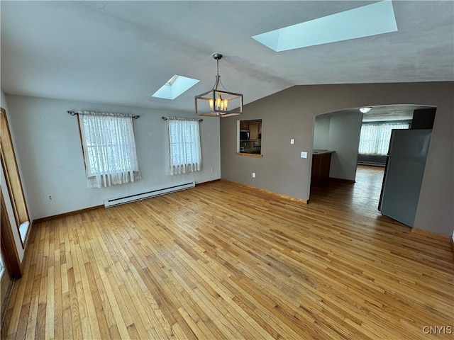 unfurnished room featuring plenty of natural light, light wood finished floors, baseboard heating, and lofted ceiling with skylight