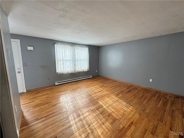 empty room with light wood finished floors, a baseboard radiator, and baseboards