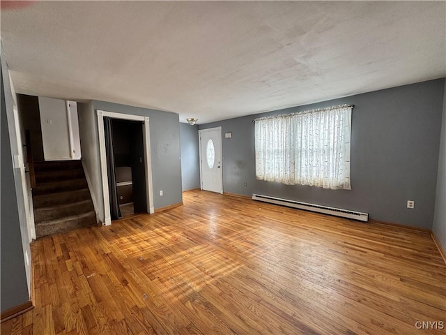 unfurnished living room with stairs, baseboards, baseboard heating, and wood finished floors