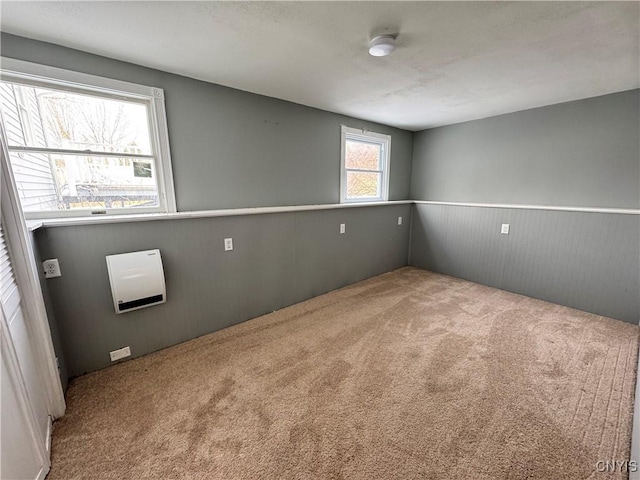 carpeted empty room featuring a wainscoted wall