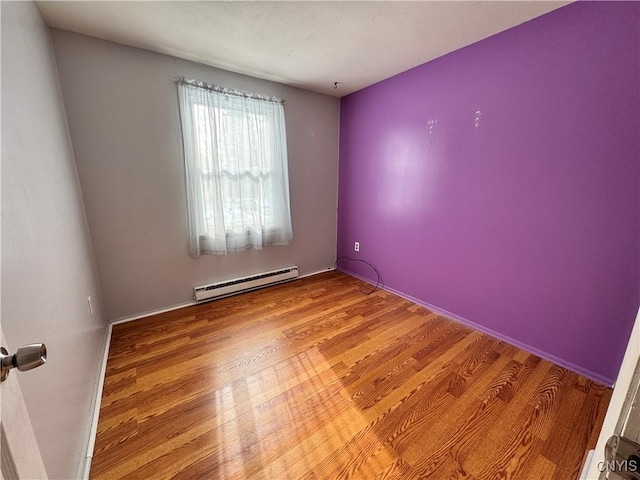 spare room with baseboard heating and wood finished floors