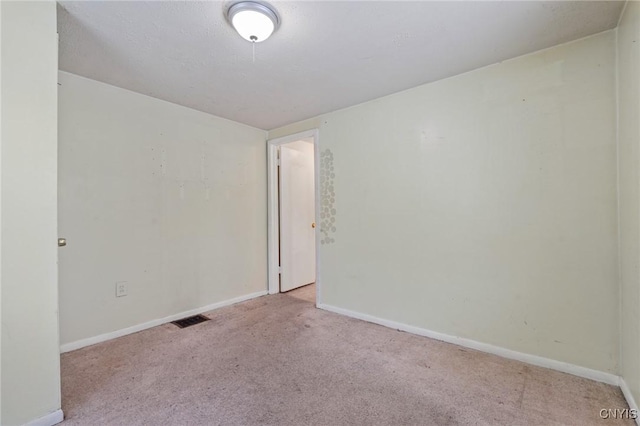 unfurnished room with baseboards, visible vents, and light colored carpet