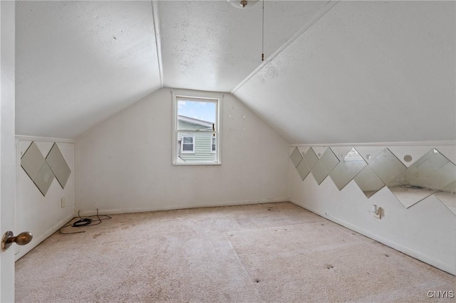 bonus room with lofted ceiling, light carpet, and a textured ceiling