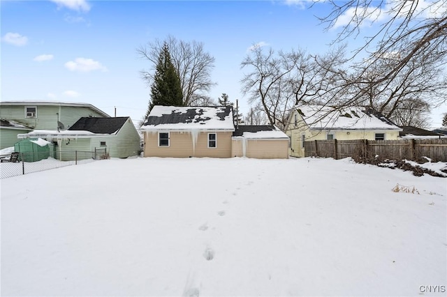 snowy yard featuring a detached garage and fence