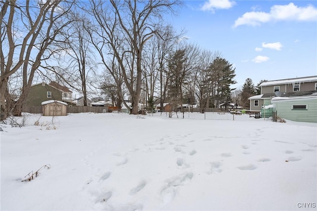 snowy yard featuring a storage unit and fence