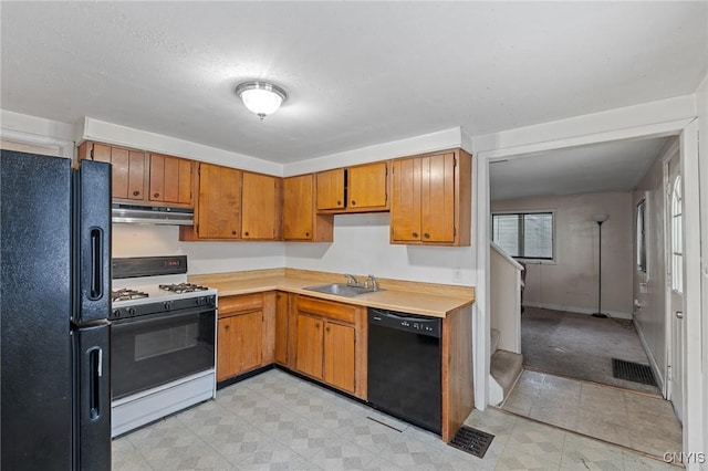 kitchen with light floors, under cabinet range hood, a sink, light countertops, and black appliances